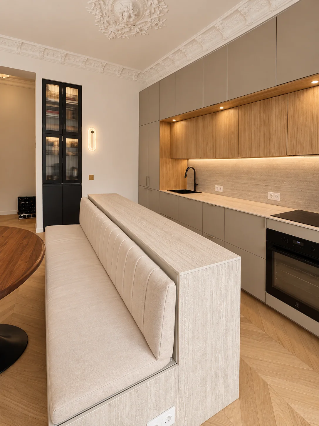 Cuisine et banquette du projet Demours, vues depuis le séjour sous un plafond à moulures.