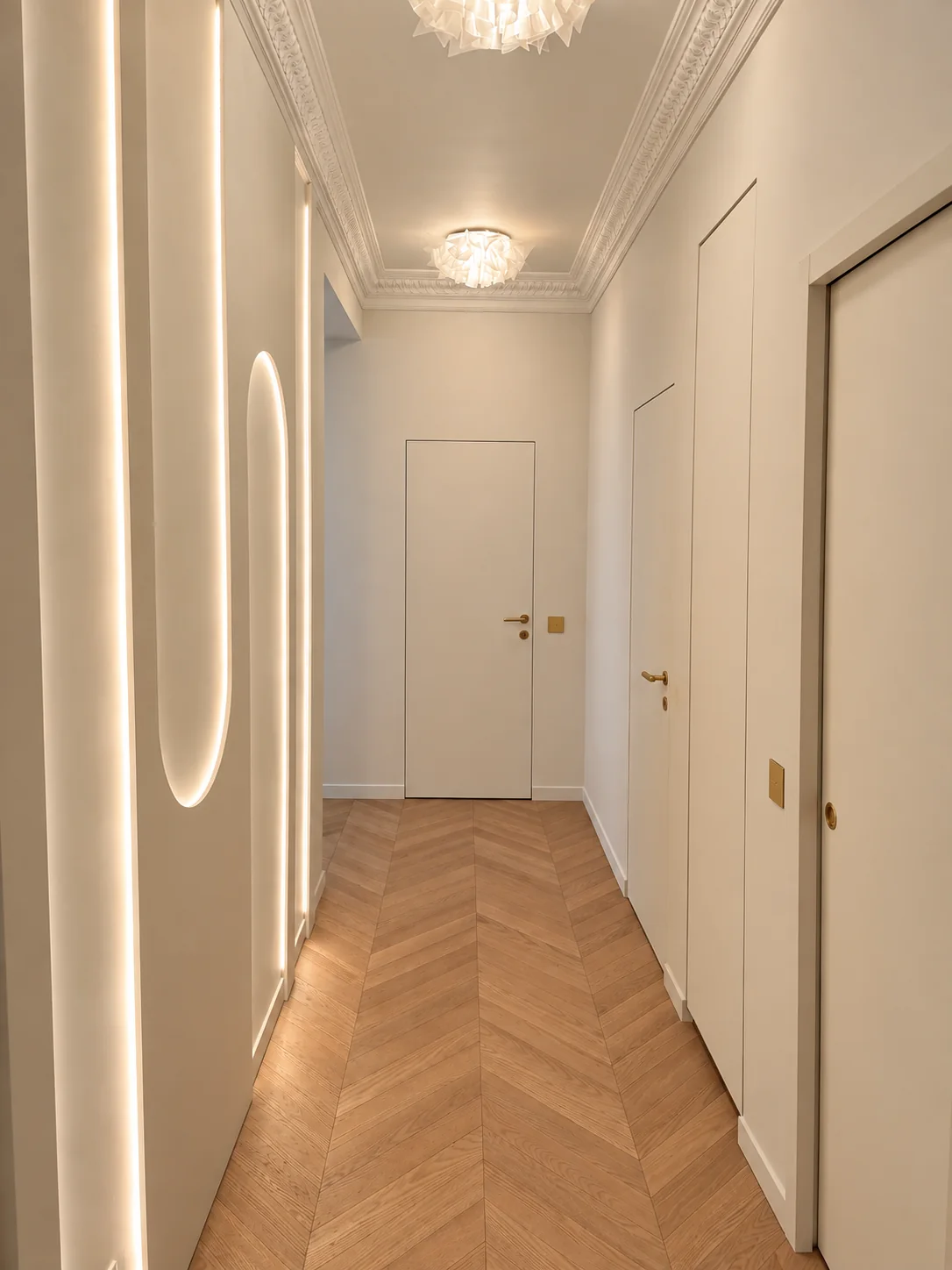 Entrée du projet Demours, parquet en point de Hongrie, moulures et niches lumineuses.