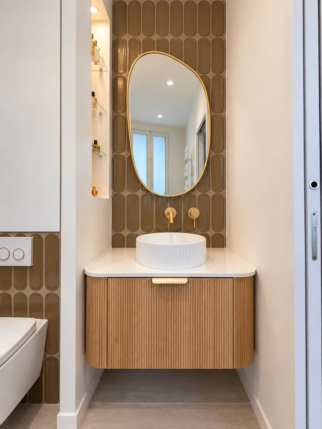 Salle de bains du projet Demours, vasque blanche sur meuble en bois et miroir ovale.