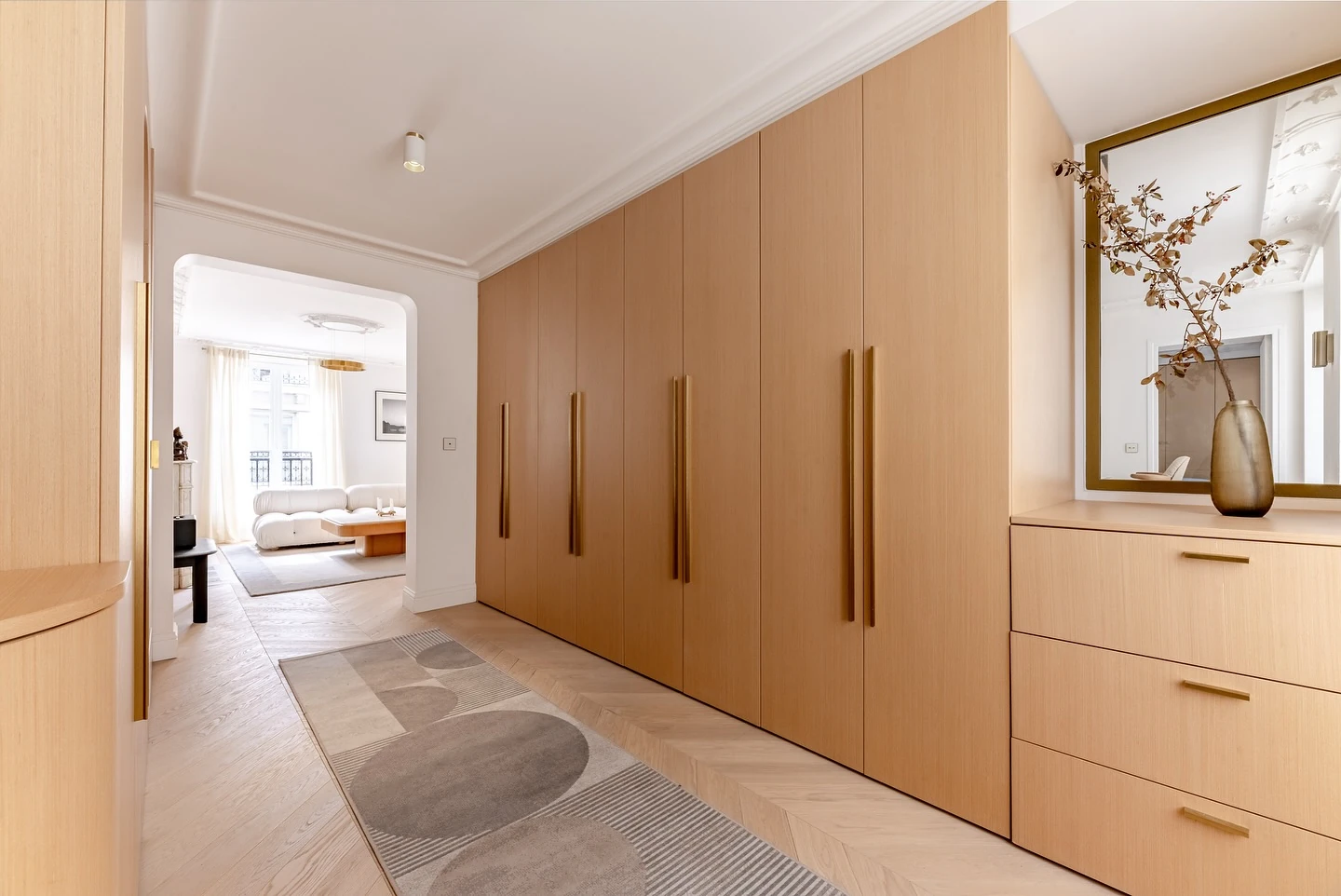 Entrée de l’appartement Odéon, menuiseries en bois, miroir et perspective vers le séjour.