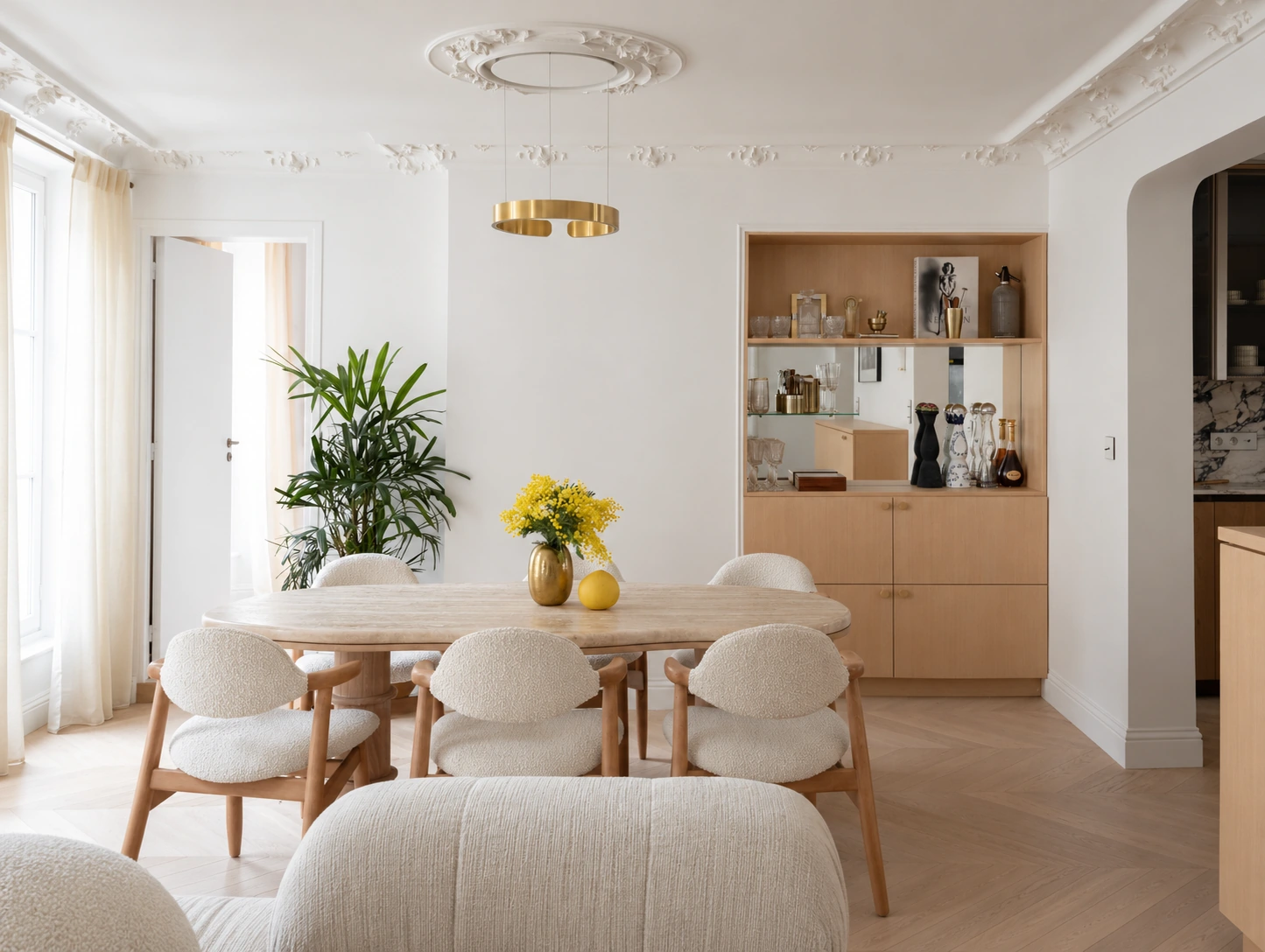 Salle à manger du projet Odéon, table en pierre claire, chaises en bois et bar intégré sur mesure.