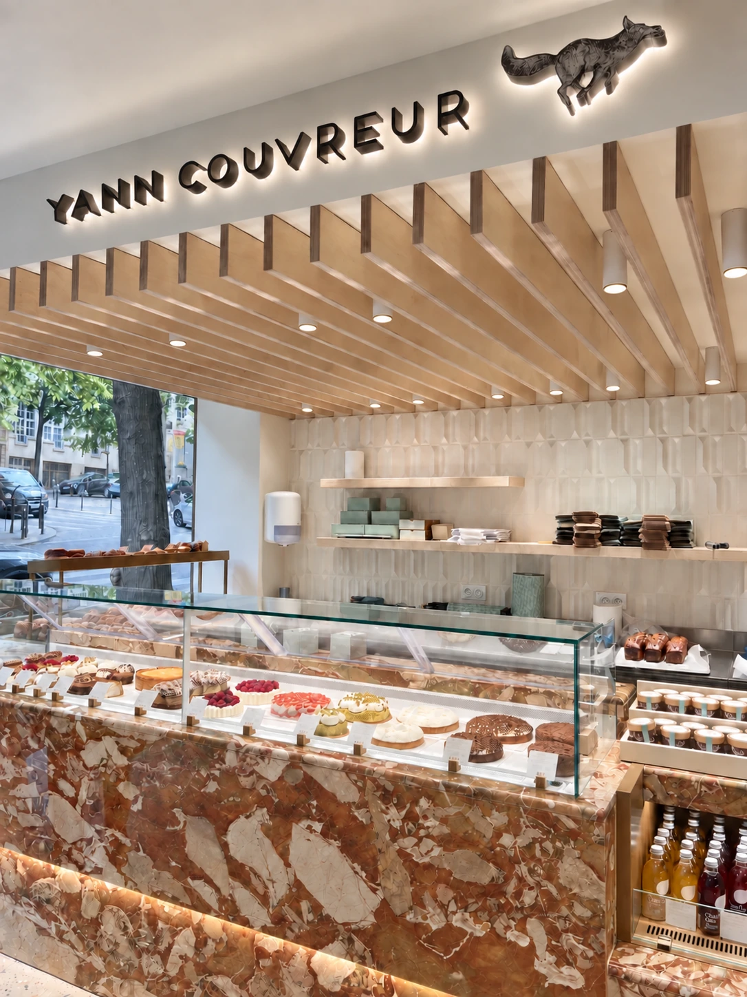 Perspective vers la vitrine de la boutique Yann Couvreur Caulaincourt, sous les éclairages du plafond en bois.
