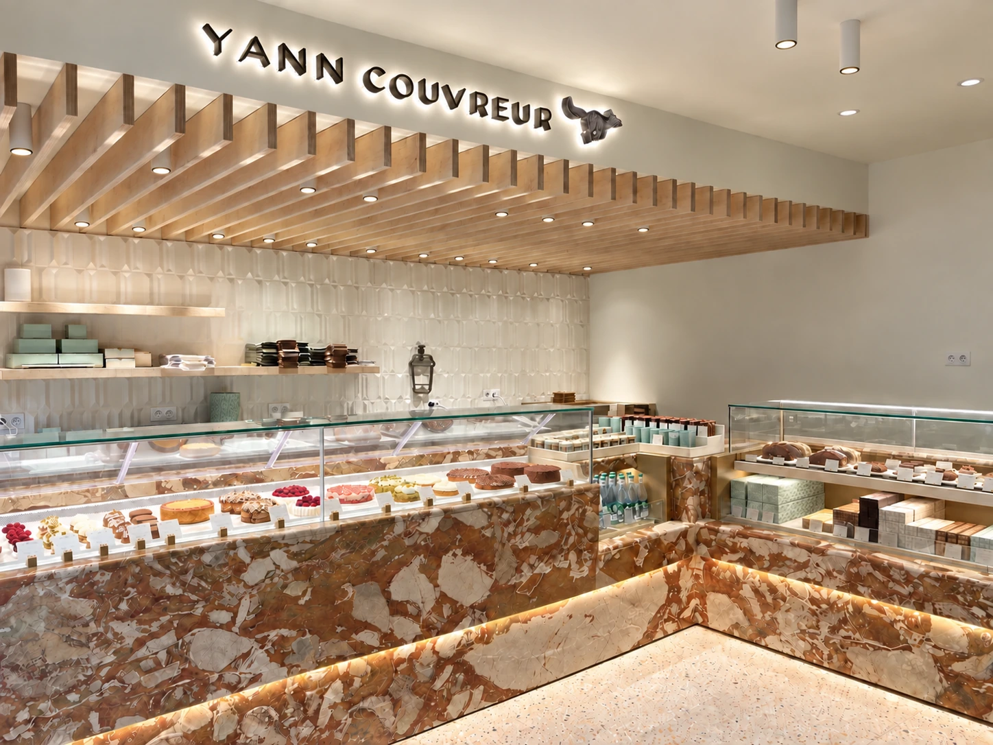 Boutique Yann Couvreur Caulaincourt à Paris, comptoirs en pierre et plafond à lames de bois éclairées.